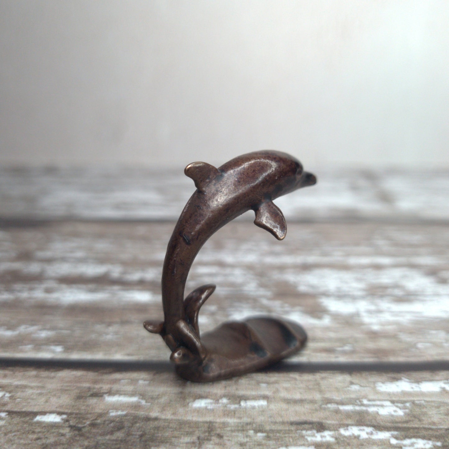 Miniature bronze dolphin sculpture standing on wave base, by David Meredith at Alcove Art