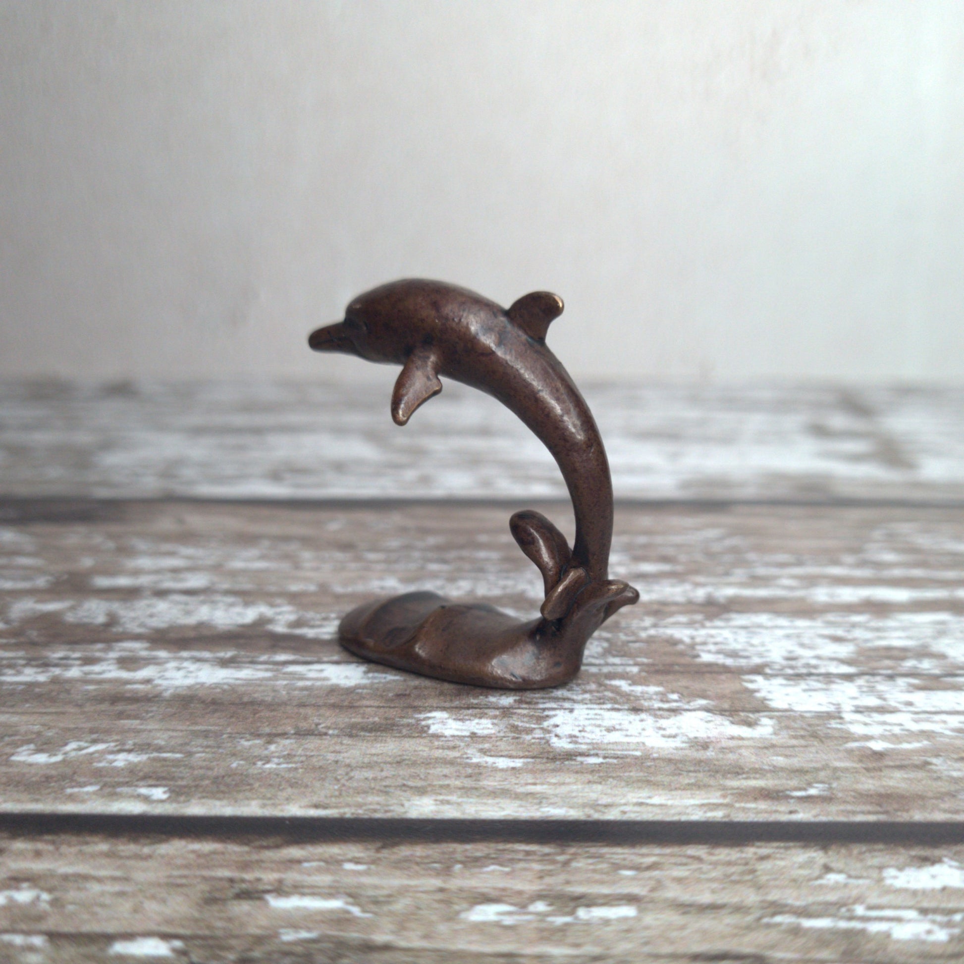 Miniature bronze dolphin sculpture standing on wave base, by David Meredith at Alcove Art