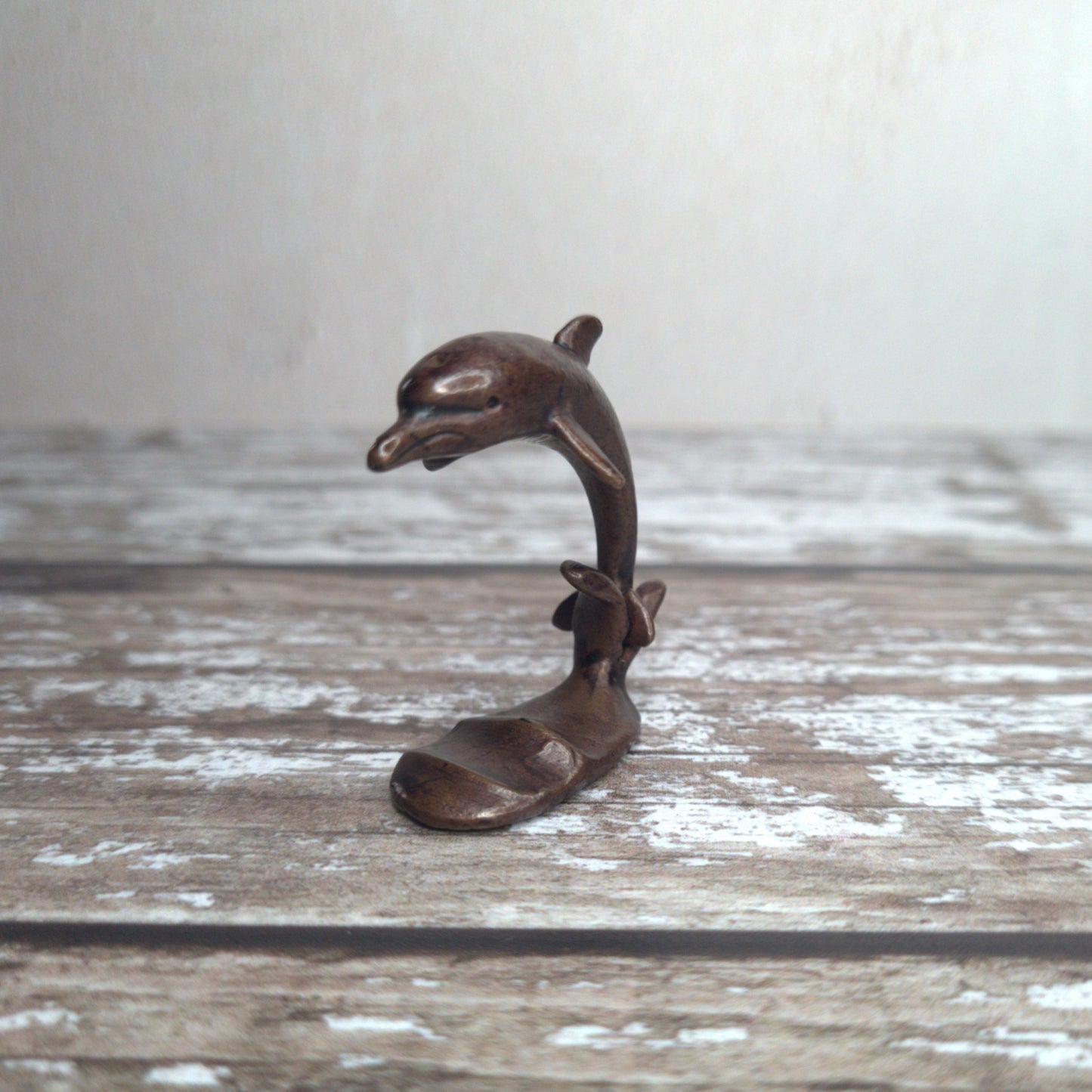 Miniature bronze dolphin sculpture standing on wave base, by David Meredith at Alcove Art