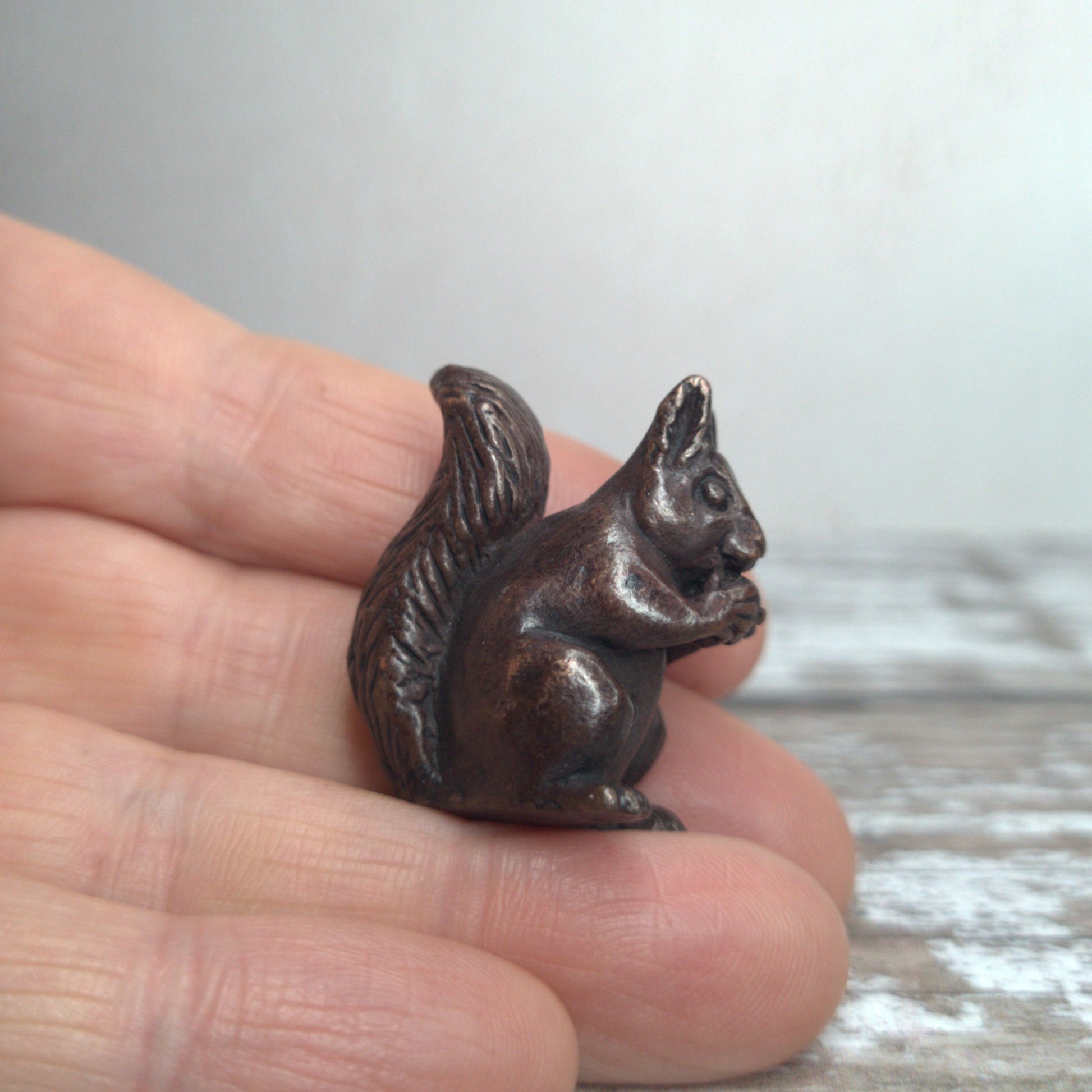 Miniature bronze squirrel sculpture held in hand to show scale, by David Meredith at Alcove Art